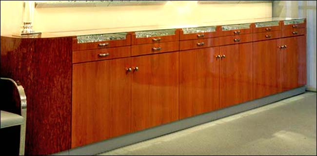 Cherry Burl Wood Eye Glass Display Counter - Front View. This modern style counter was designed for an upscale Eye Doctors office. It includes a 2 rows of pull draws with glass fronts and storage below.
