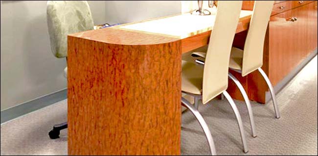 Cherry Burl Wood Consultation Desk This modern style consultation desk was designed for an upscale Eye Doctors office in Los Angeles. The desk includes a curved side storage cabinet and a solid color top inlay.