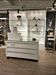 The Moderne register counter features a sturdy, white high-gloss finish and a glass top for an attractive display area. The mobility of the counter is enhanced with casters that make moving it around your space easy and efficient, so you can always keep y